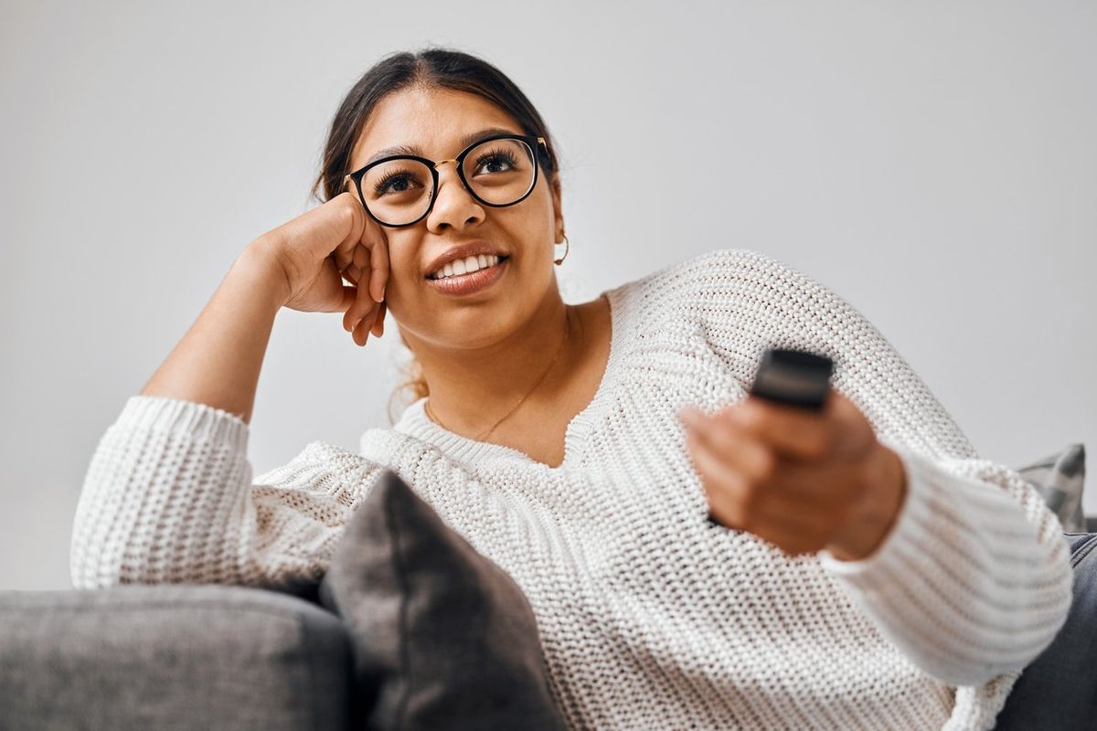 Shot of a young woman watching tv on the sofa at home stock photo