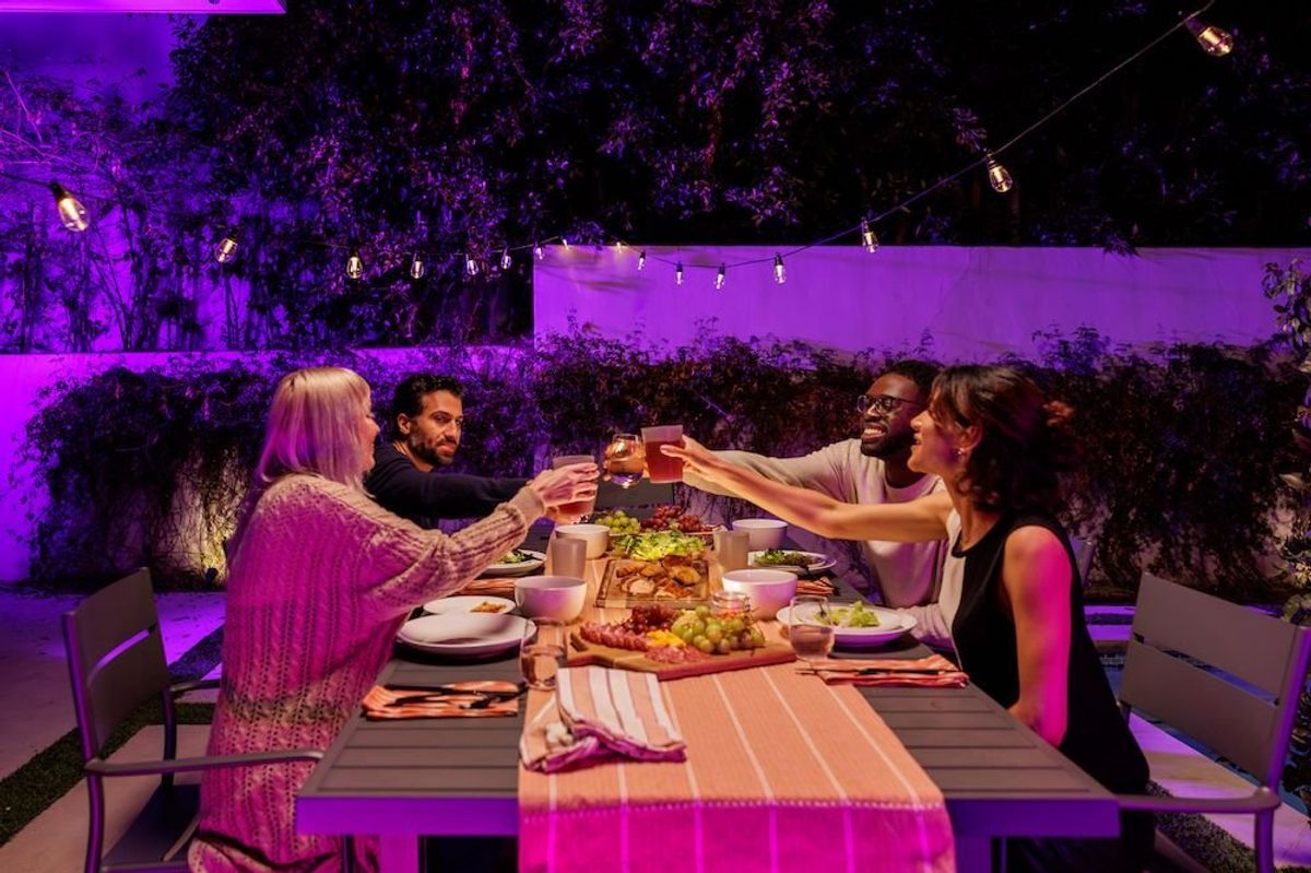 photo of two couples dining outside under Cync smart cafe lights.